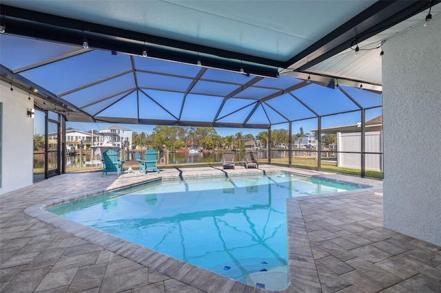 view of swimming pool featuring a water view, glass enclosure, and a patio area