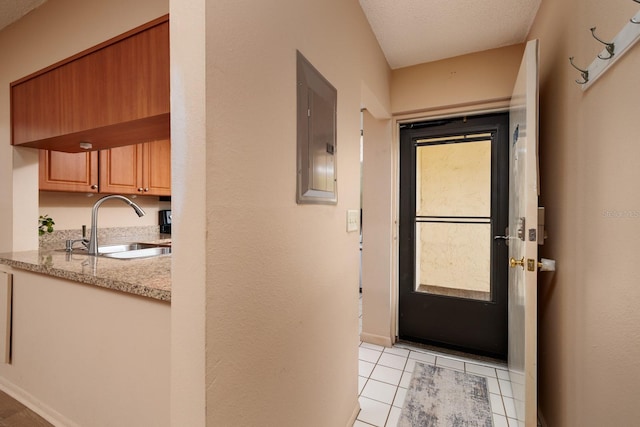 entryway with light tile patterned flooring, electric panel, sink, and a textured ceiling