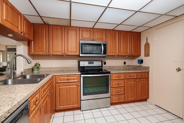 kitchen featuring appliances with stainless steel finishes, a drop ceiling, sink, and light tile patterned flooring