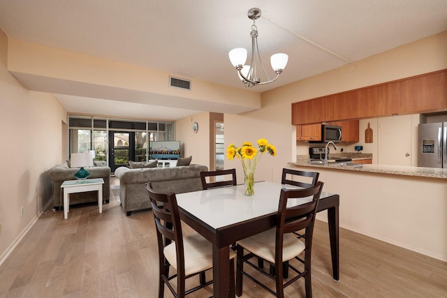 dining space featuring a notable chandelier and light wood-type flooring