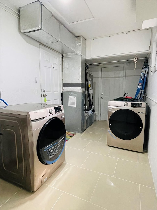 clothes washing area featuring heating unit, light tile patterned floors, and independent washer and dryer