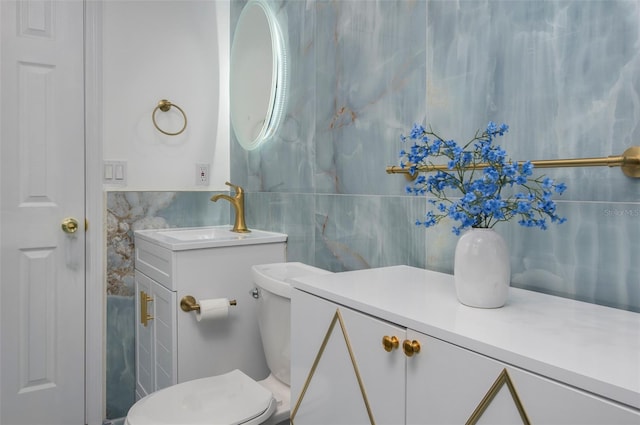 bathroom with vanity, toilet, and tile walls