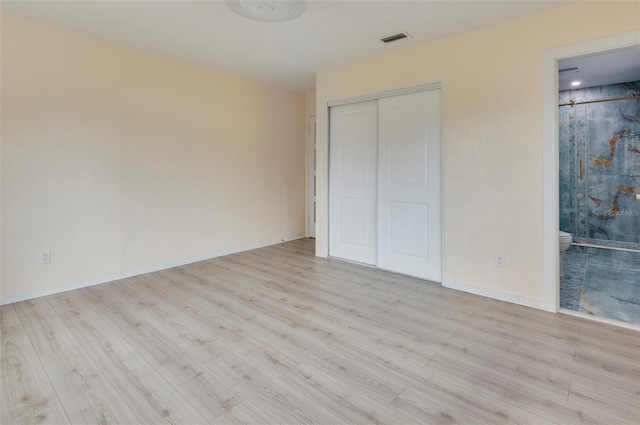 unfurnished bedroom featuring ensuite bath and light hardwood / wood-style flooring