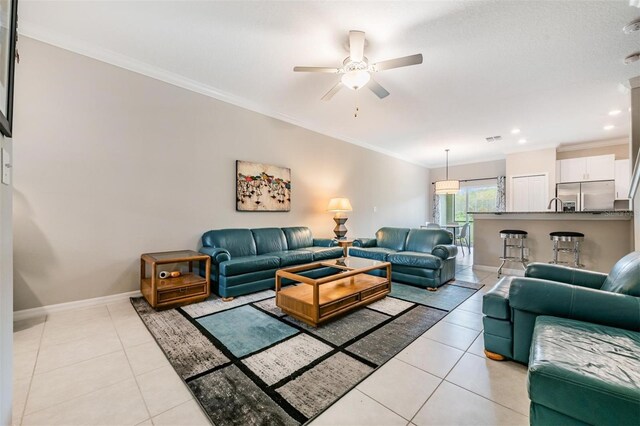 tiled living room with ceiling fan and crown molding