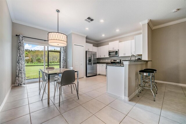 kitchen with white cabinets, kitchen peninsula, stainless steel appliances, decorative light fixtures, and crown molding