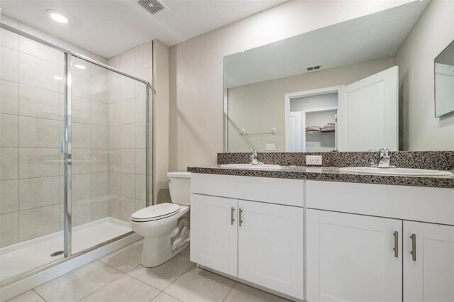 bathroom with walk in shower, vanity, toilet, and tile patterned floors