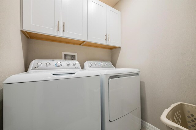 clothes washing area featuring cabinets and washing machine and clothes dryer