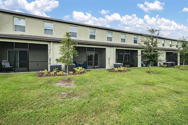 back of house featuring a sunroom, a lawn, and central AC