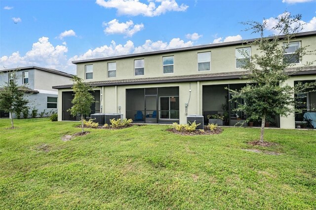 back of property with a yard, a sunroom, and central AC unit