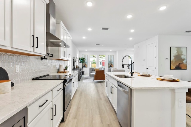 kitchen with appliances with stainless steel finishes, light stone counters, white cabinets, wall chimney exhaust hood, and sink