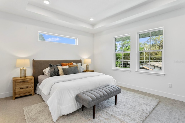 bedroom with a tray ceiling and light colored carpet