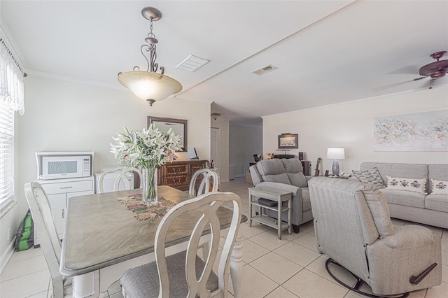 tiled dining space featuring crown molding and ceiling fan