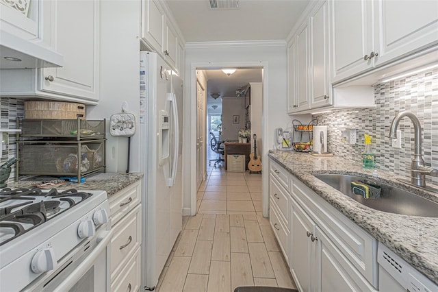 kitchen with light stone counters, sink, white appliances, extractor fan, and white cabinetry