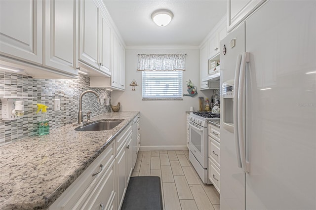 kitchen featuring light stone counters, sink, tasteful backsplash, white appliances, and white cabinetry