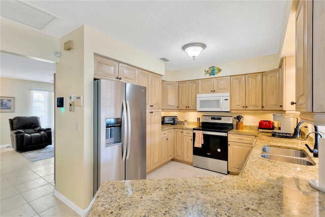 kitchen featuring appliances with stainless steel finishes, light stone countertops, sink, and light brown cabinetry