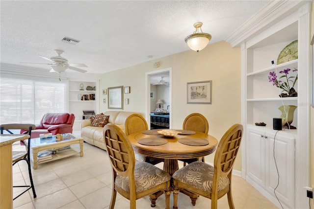 tiled dining space with a textured ceiling, built in features, and ceiling fan