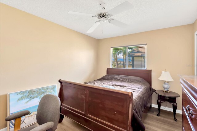 bedroom featuring light hardwood / wood-style flooring, a textured ceiling, and ceiling fan