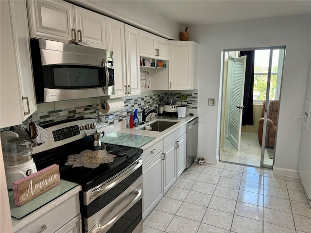 kitchen with appliances with stainless steel finishes, tasteful backsplash, sink, light tile patterned floors, and white cabinets