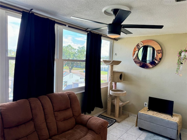 tiled living room with a wealth of natural light, ceiling fan, and a textured ceiling