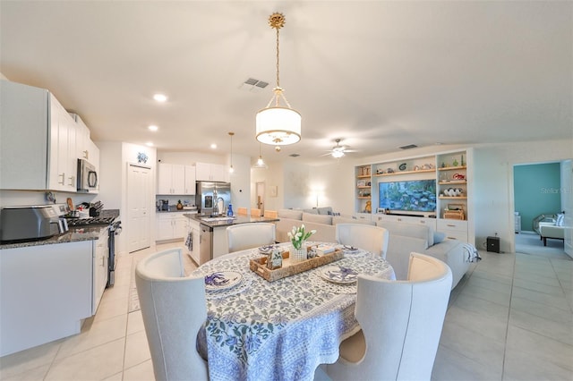 tiled dining area with ceiling fan and sink