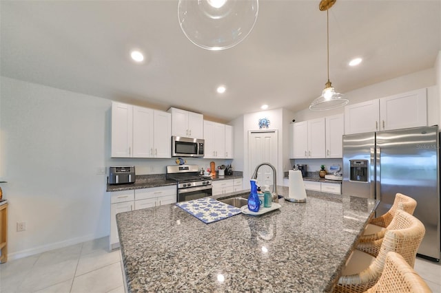 kitchen with white cabinets, a kitchen island with sink, sink, and stainless steel appliances