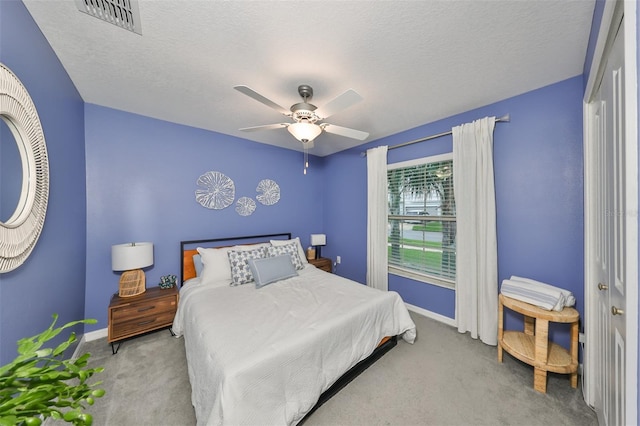 bedroom featuring a textured ceiling, ceiling fan, a closet, and light colored carpet