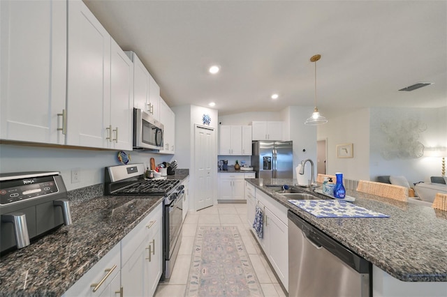 kitchen with light tile patterned floors, stainless steel appliances, a kitchen island with sink, white cabinets, and sink