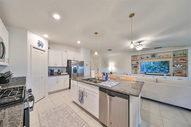 kitchen featuring sink, appliances with stainless steel finishes, an island with sink, white cabinets, and dark stone counters