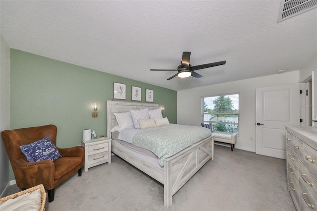 bedroom featuring ceiling fan, light carpet, and a textured ceiling