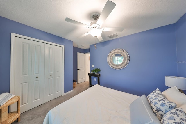 bedroom with a textured ceiling, ceiling fan, carpet, and a closet