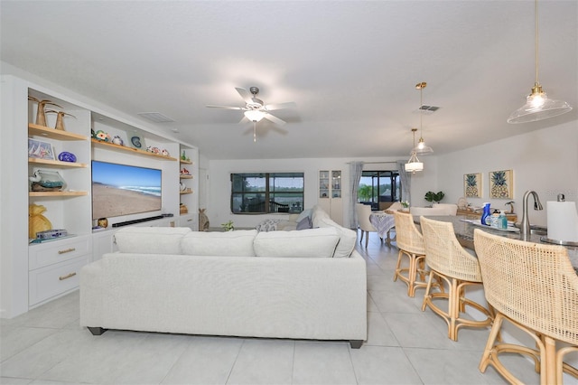 living room with ceiling fan, sink, built in shelves, and light tile patterned floors