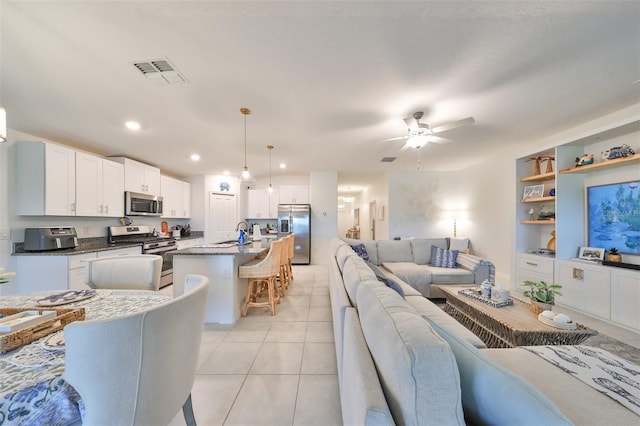 living room with ceiling fan, light tile patterned flooring, and sink