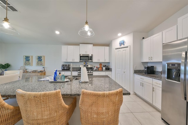 kitchen with stainless steel appliances, white cabinets, and a center island with sink