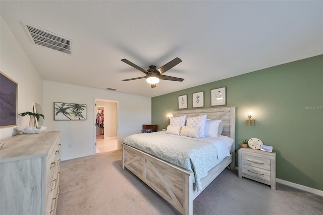 carpeted bedroom featuring ceiling fan and a walk in closet