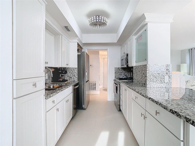 kitchen with sink, appliances with stainless steel finishes, tasteful backsplash, dark stone counters, and white cabinets