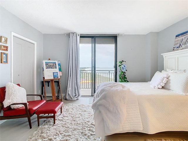 bedroom featuring access to outside, a water view, and a closet