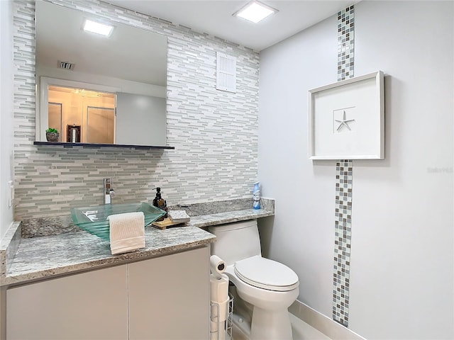 bathroom featuring toilet, tasteful backsplash, and vanity