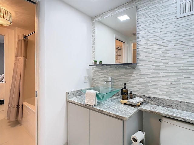 bathroom featuring vanity, decorative backsplash, and shower / tub combo