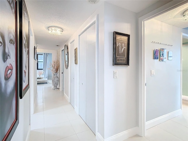 hall with a textured ceiling and light tile patterned floors