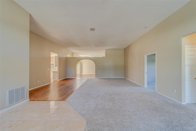 unfurnished living room with light hardwood / wood-style flooring and a textured ceiling