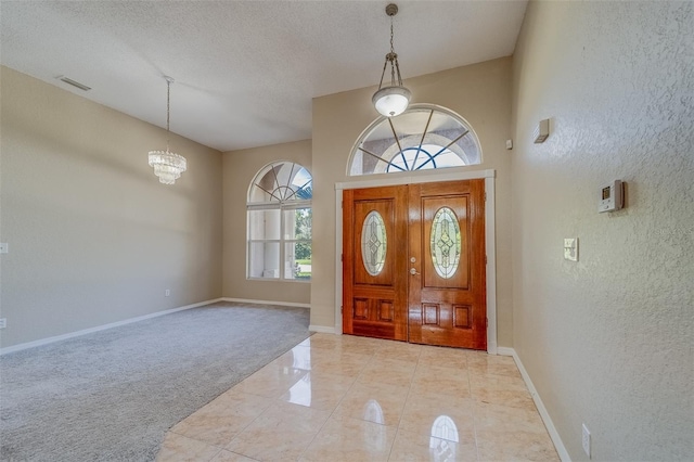 carpeted foyer entrance with a towering ceiling, a textured ceiling, and an inviting chandelier