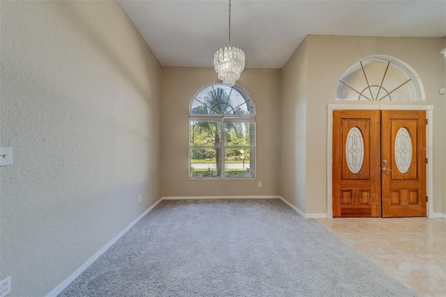 carpeted entrance foyer with a notable chandelier