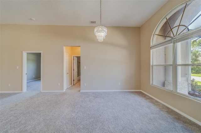 unfurnished room featuring light carpet and an inviting chandelier