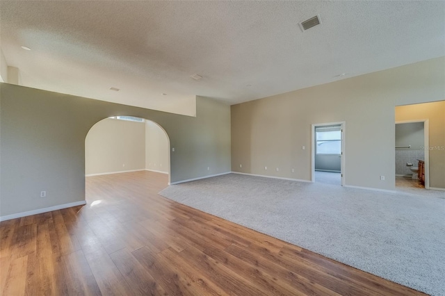 empty room with wood-type flooring and a textured ceiling