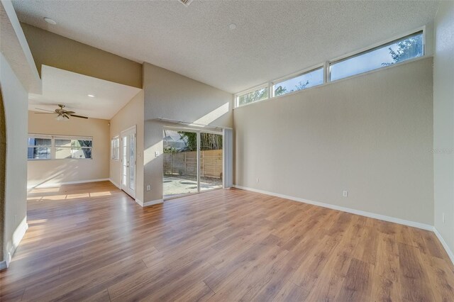 unfurnished living room featuring ceiling fan, light hardwood / wood-style floors, a textured ceiling, and high vaulted ceiling