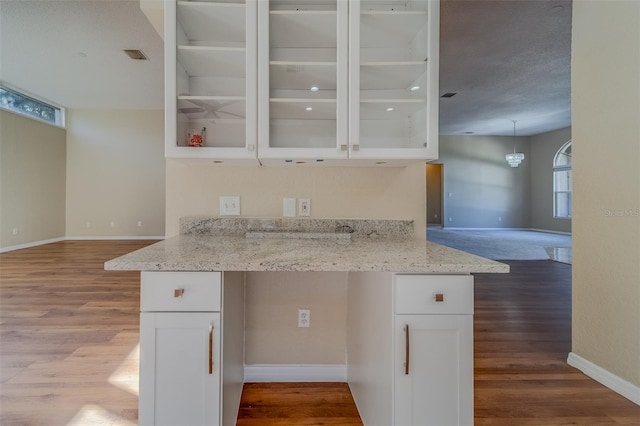 kitchen featuring light stone countertops, light wood-type flooring, and white cabinetry