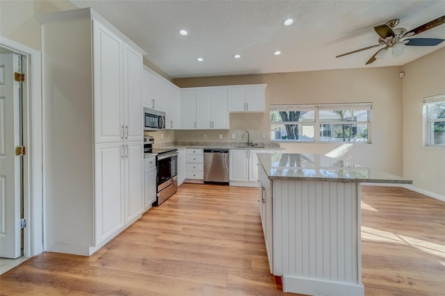 kitchen with sink, white cabinets, light hardwood / wood-style floors, and appliances with stainless steel finishes