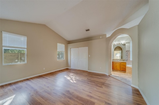 unfurnished room with light hardwood / wood-style floors, plenty of natural light, and lofted ceiling