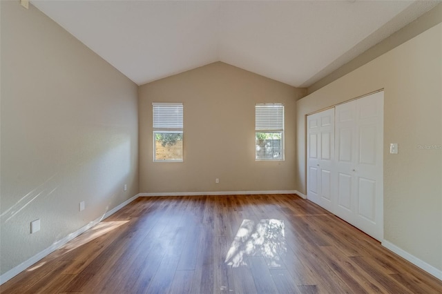 unfurnished bedroom featuring hardwood / wood-style floors, a closet, and vaulted ceiling