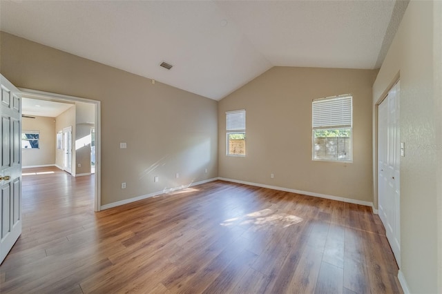 unfurnished room with light hardwood / wood-style floors and vaulted ceiling